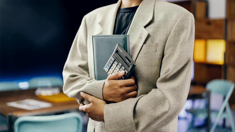 A finance professional holding a calculator and a folder, standing for accounting and tax work in the UAE