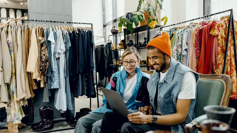 Two people going through stock on a laptop in a clothing shop, standing for retail and food businesses in the UAE